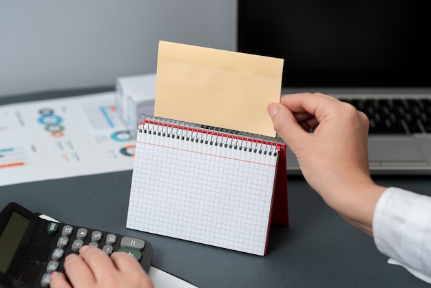 Geschäftsfrau Holding Hinweis mit aktuellen Nachricht auf dem Schreibtisch mit Notebook mit neuen Ideen Frau im Anzug mit Memo mit den letzten Updates in der Hand auf dem Tisch mit Notepad mit späten Daten