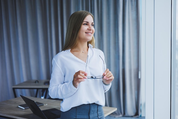 Geschäftsfrau im Büro mit Brille in ihren Händen Managerin mit Brille und weißem Hemd im Büro Manager für Arbeitstage