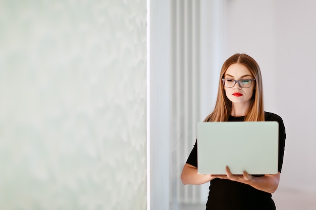 Geschäftsfrau im schwarzen Kleid mit Laptop