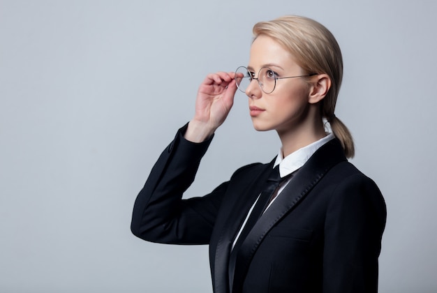 Geschäftsfrau in einem klassischen schwarzen Business-Anzug und Brille