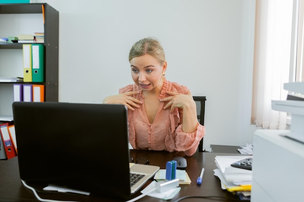 Geschäftsfrau kommuniziert per Videoanruf, während sie in einen Laptop schaut, während sie an einem Tisch in ihrem Büro sitzt Online-Konferenz Videoanruf