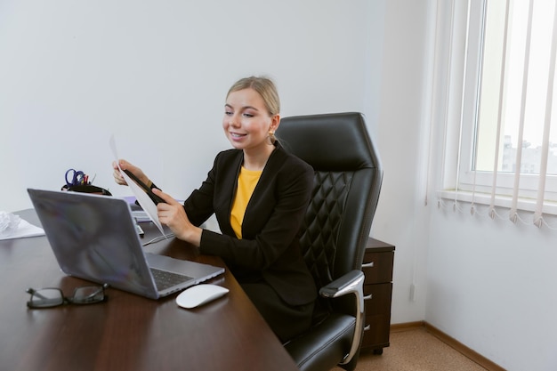 Geschäftsfrau kommuniziert per Videokonferenz, während sie in einen Laptop schaut, während sie an einem Tisch in ihrem Büro sitzt Online-Konferenz Videoanruf