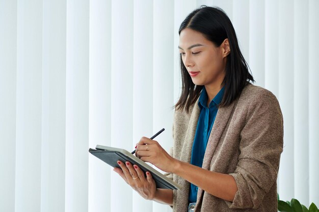 Geschäftsfrau macht sich Notizen auf dem Tablet