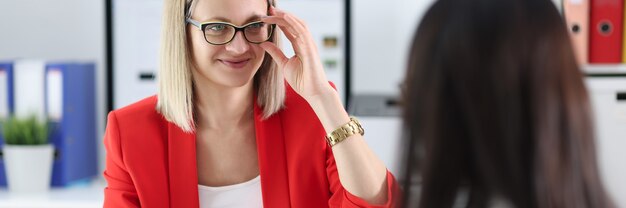 Geschäftsfrau mit Brille, die mit Kollegen am Tisch kommuniziert