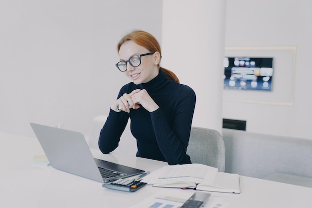 Geschäftsfrau mit Brille hat Online-Business-Videokonferenz und lächelt in die Kamera