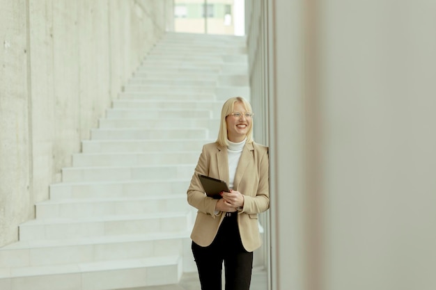 Geschäftsfrau mit digitalem tablet auf modernem büroflur