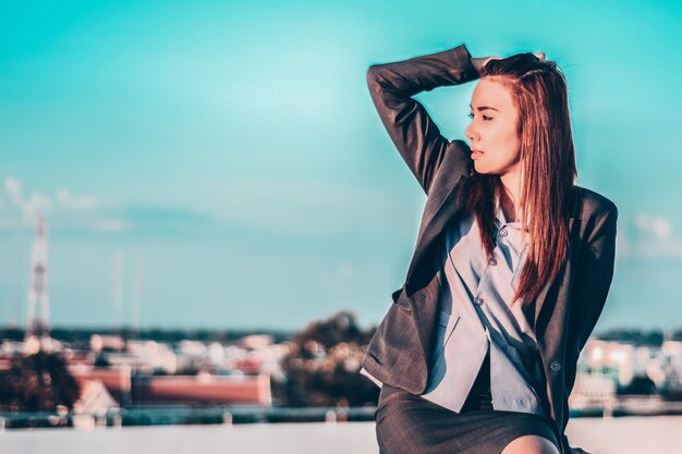 Foto geschäftsfrau mit hand in den haaren sitzt gegen den himmel