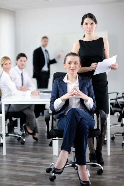 Geschäftsfrau mit ihren Mitarbeitern, Personengruppe im Hintergrund im modernen, hellen Büro im Innenbereich