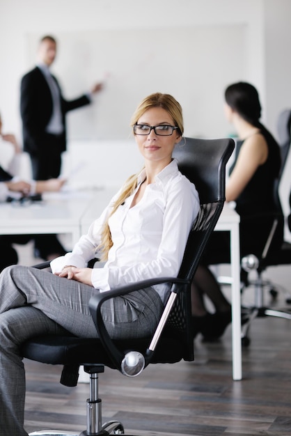 Foto geschäftsfrau mit ihren mitarbeitern, personengruppe im hintergrund im modernen, hellen büro im innenbereich