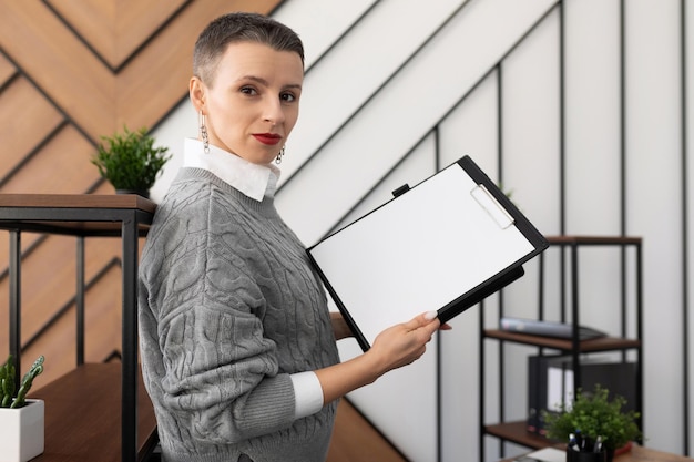 Geschäftsfrau mit kurzem Haarschnitt mit einem Ordner für Dokumente in den Händen im Büro suchen