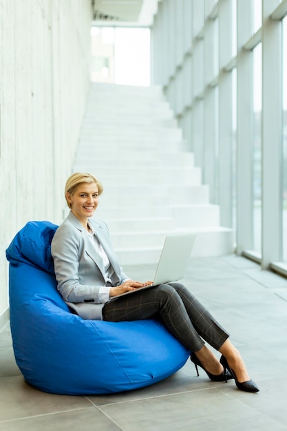 Geschäftsfrau mit Laptop-Computer auf Lazy Bag im modernen Büro