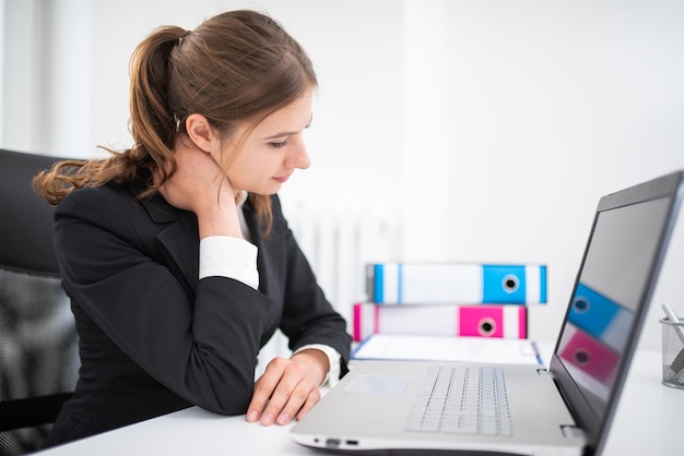 Geschäftsfrau mit Nackenschmerzen im Büro