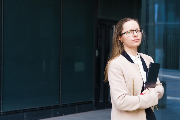 Geschäftsfrau mit Ordner in der Hand und Brille in der Nähe des Geschäftszentrums