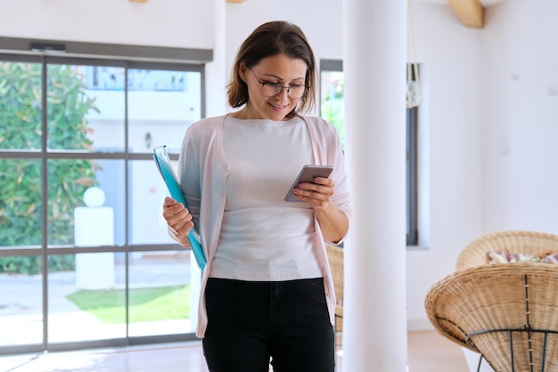 Geschäftsfrau mit Smartphone und Zwischenablage im Hotelinterieur.