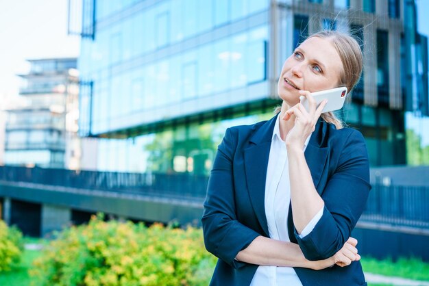 Geschäftsfrau mit Telefon in der Nähe von Büro Schönes lächelndes Mädchen des Porträts