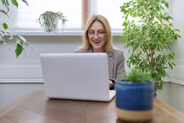 Geschäftsfrau mittleren Alters, die zu Hause mit Laptop arbeitet