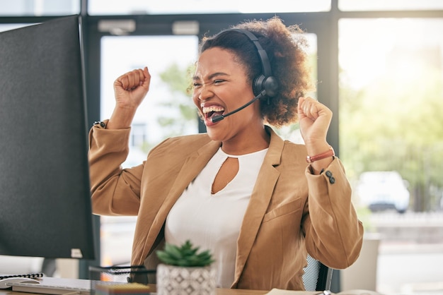 Geschäftsfrau ruft im Callcenter an und feiert am Computer den Gewinn von Verkaufsprämien oder Telemarketing-Zielen. Glückliche afrikanische Beraterin mit Stolz auf ihre Erfolge oder einer Handvoll guter Nachrichten am Desktop