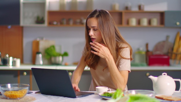 Geschäftsfrau schließt Laptop nach der Arbeit in der Küche. Dame geht von zu Hause weg