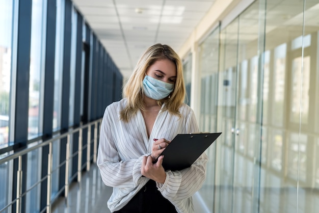 Geschäftsfrau schreibt in ein Tablet, während sie im Flur eines modernen Geschäftszentrums steht