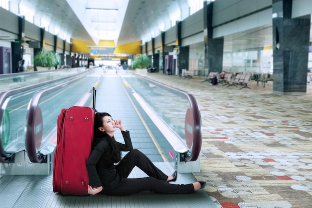 Geschäftsfrau sitzt auf dem Boden am Flughafen