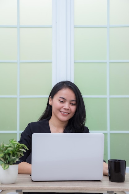 Geschäftsfrau sitzt auf einem Stuhl und hat ein Online-Meeting mit Laptop