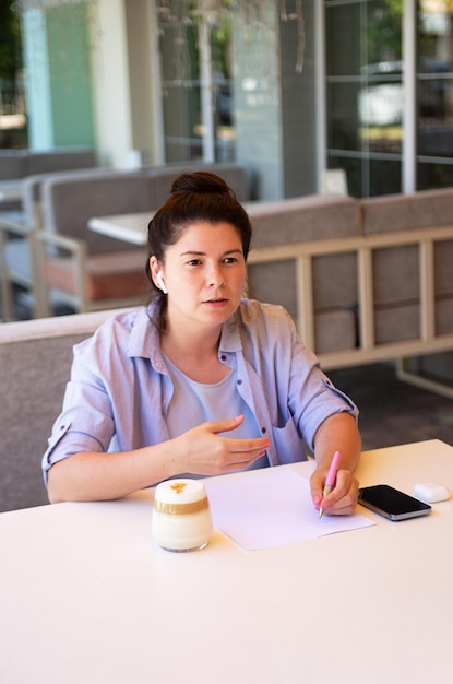 Geschäftsfrau sitzt draußen mit ihrem Handy und unterschreibt documentVertical-Fotografie