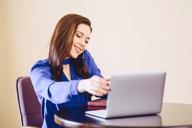 Geschäftsfrau spricht telefonisch im Büro und arbeitet an Laptop