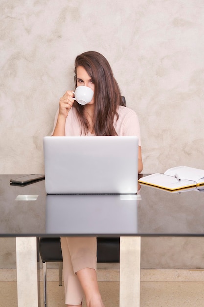 Geschäftsfrau trinkt Kaffee vor ihrem Laptop zu Hause