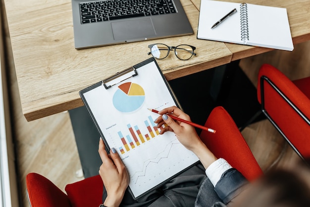 Geschäftsfrau überprüft Diagramme und aktualisiert den finanziellen Fortschritt. Das Mädchen analysiert das Geschäftsmodell am Arbeitsplatz.