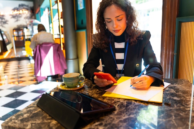 Geschäftsfrau überprüft E-Mails mit dem Handy in einem Café