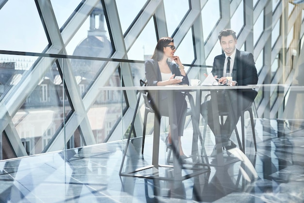 Geschäftsfrau und Geschäftsmann unterhalten sich am Schreibtisch im modernen Büro