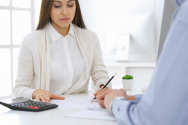 Geschäftsfrau und Mann sitzen und arbeiten mit Computer und Taschenrechner im Büro