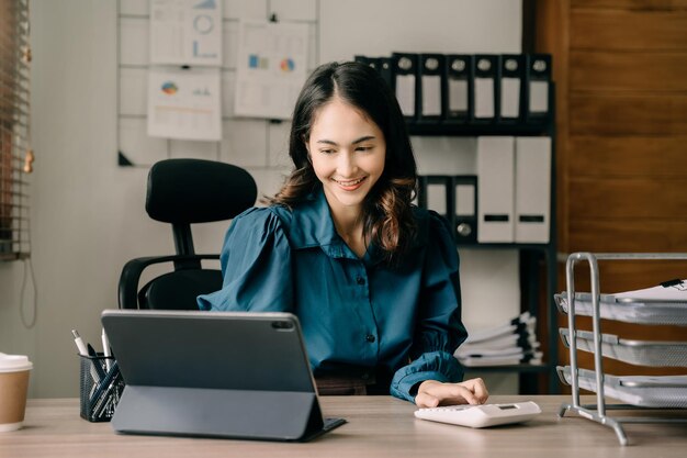 Geschäftsfrauen arbeiten mit Tablet und Taschenrechner mit Dokumenten auf dem Schreibtisch im modernen Büro