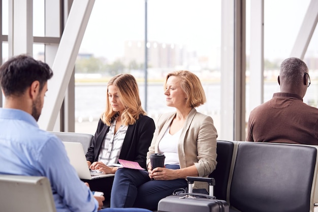 Geschäftsfrauen, die im Flughafen sitzen, arbeiten am Laptop und trinken Kaffee