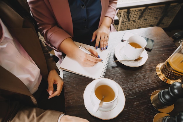 Geschäftsfrauen sitzen in einem Café, trinken Kaffee und führen ein Geschäftsgespräch, besprechen Geschäfte und haben Spaß