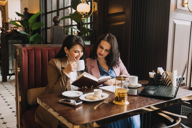 Geschäftsfrauen sitzen in einem Café, trinken Kaffee und führen ein Geschäftsgespräch, besprechen Geschäfte und haben Spaß