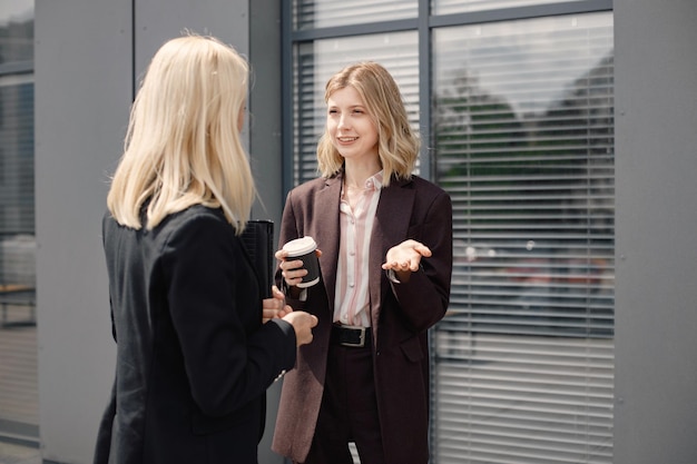 Geschäftsfrauen stehen und sprechen vor modernen Büros miteinander