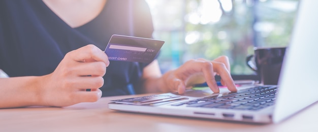 Geschäftsfrauen übergeben Kreditkarten und Laptop-Computer, um online zu kaufen.