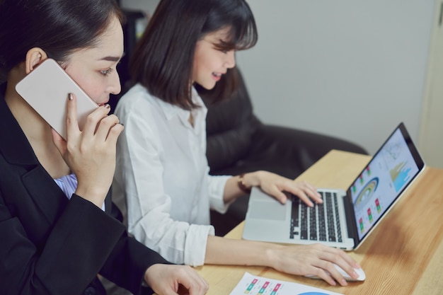 Geschäftsfrauen verwenden Laptops und Smartphones, um im Büro zu arbeiten.