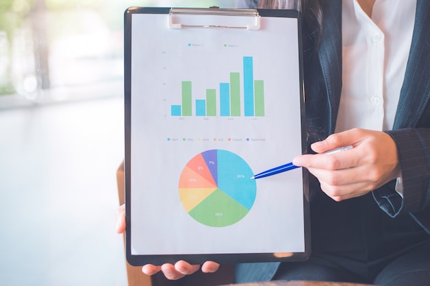 Geschäftsfrauhandarbeit an den Diagrammen und an den Diagrammen, die Ergebnisse zeigen.