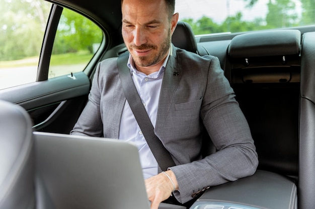 Foto geschäftsführer arbeitet bei einem laptop im auto während der morgendlichen pendelfahrt