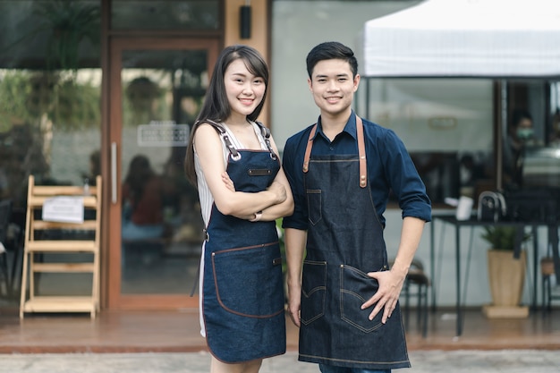 Geschäftsinhaber, die am Eingang des neu eröffneten Restaurants stehen und sich darauf vorbereiten, einen Kunden zu bedienen