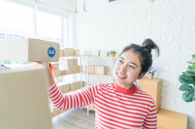 Geschäftsinhaberin der asiatischen Frauen, die zu Hause mit Packbox am Arbeitsplatz arbeitet