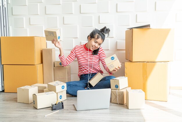 Geschäftsinhaberin der asiatischen Frauen, die zu Hause mit Packbox am Arbeitsplatz arbeitet