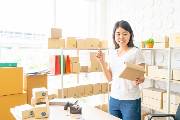 Geschäftsinhaberin der asiatischen Frauen, die zu Hause mit Packbox am Arbeitsplatz arbeitet