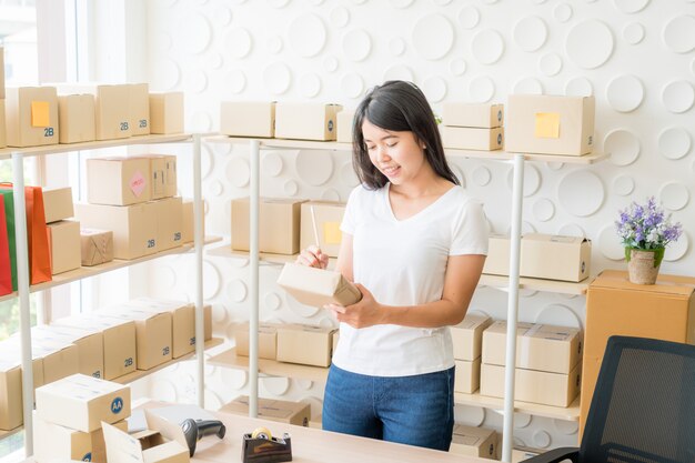 Geschäftsinhaberin der asiatischen Frauen, die zu Hause mit Packbox am Arbeitsplatz arbeitet