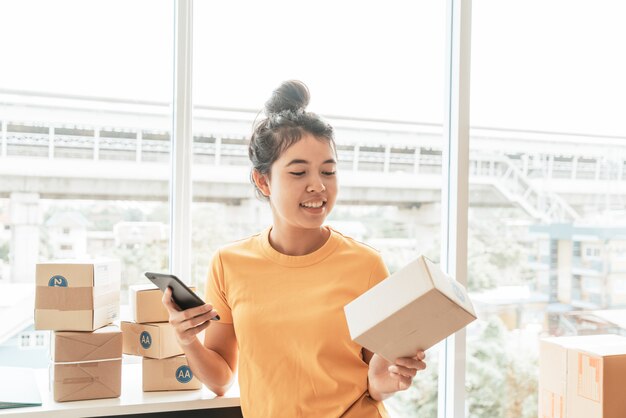 Geschäftsinhaberin der asiatischen Frauen, die zu Hause mit Packbox am Arbeitsplatz arbeitet