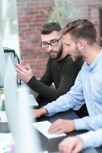 Geschäftskollegen unterhalten sich an einem Computertisch sitzend über Menschen und Technik