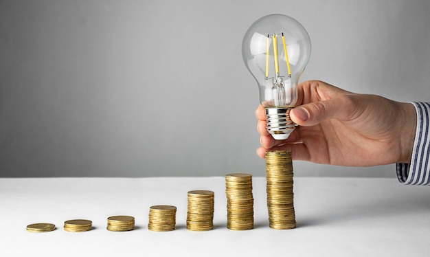 Geschäftskonzept. Eine Hand hält eine Lampe über Münzen auf hellem Hintergrund. Geschäftsideen, Brainstorming. Erholung und Geschäftswachstum. Platz kopieren