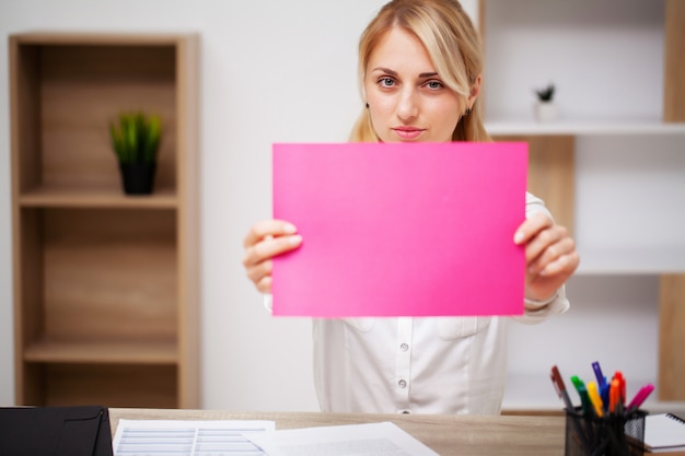 Geschäftskonzept, Frau, die leeres Blatt Papier mit Platz für Text am Arbeitsplatz hält